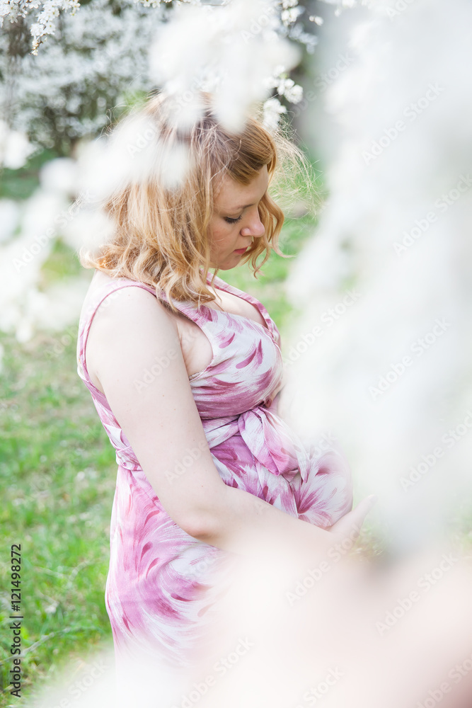 Pregnant woman standing near a flowering tree Pregnant woman standing near a flowering tree