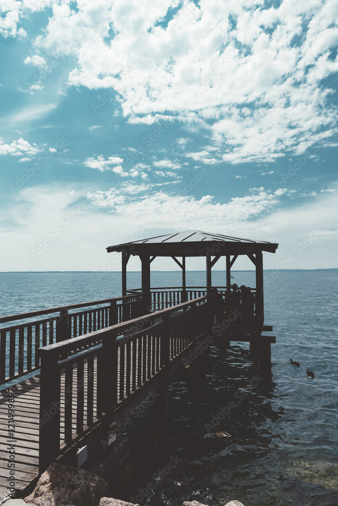 Pier on the Garda lake in a sunny day with clouds