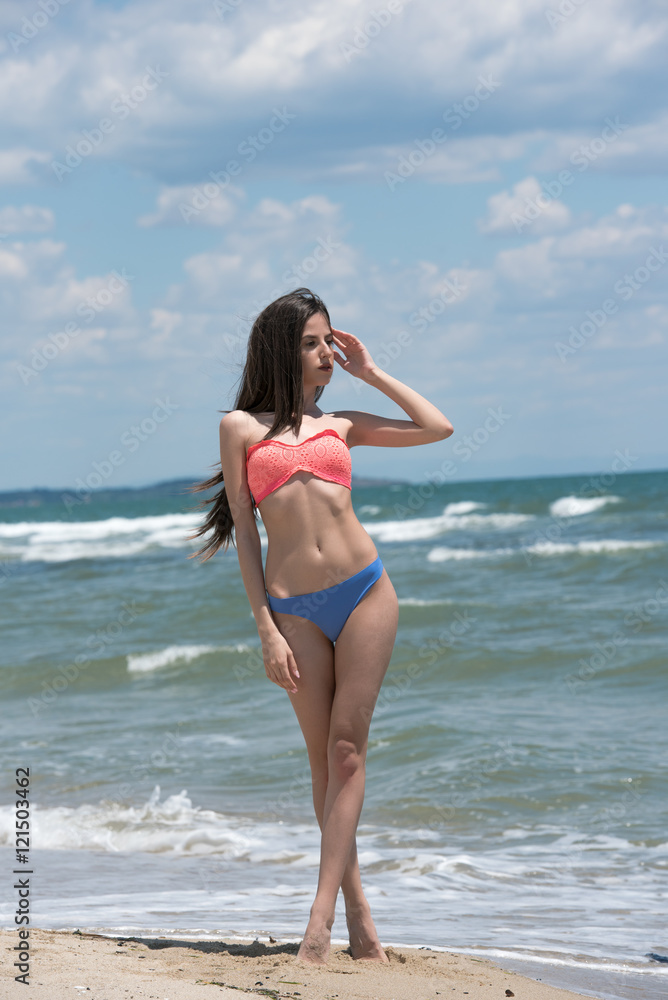 Slim girl wear bikini, beach with wild waves, vertical and full body length photo