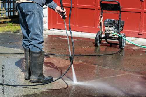 Man Cleaning Driveway with Portable Pressure Power Washer photo