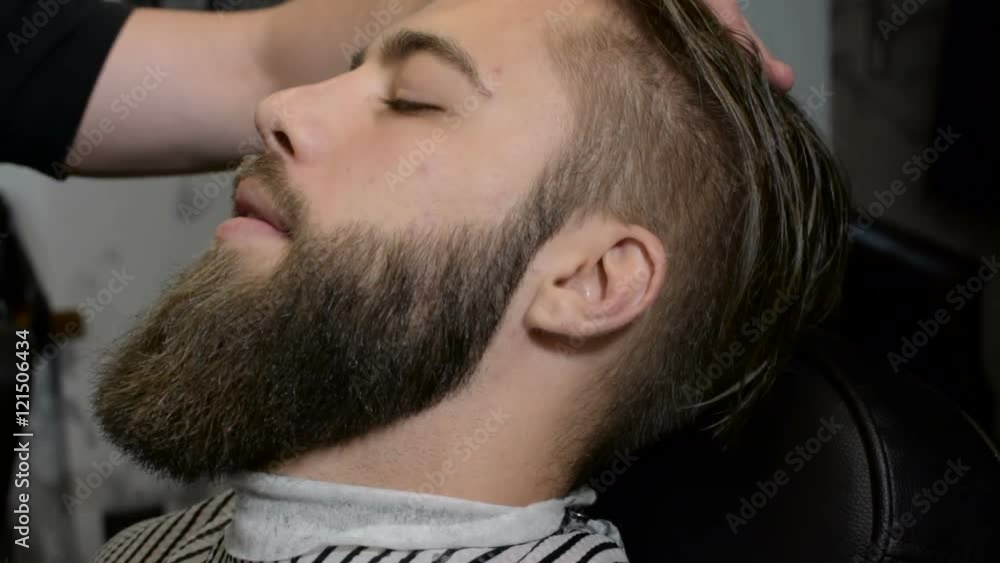 Professional hairdresser shaving man's chin with a straight razor in barbershop Professional hairdresser shaving man's chin with a straight razor in barbershop