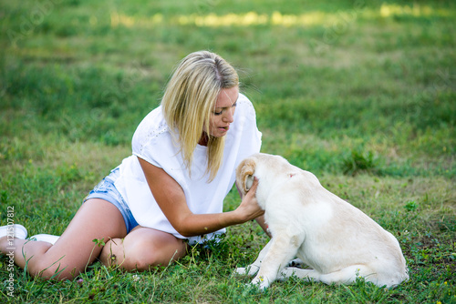 Beautiful girl playing with a puppy labrador.