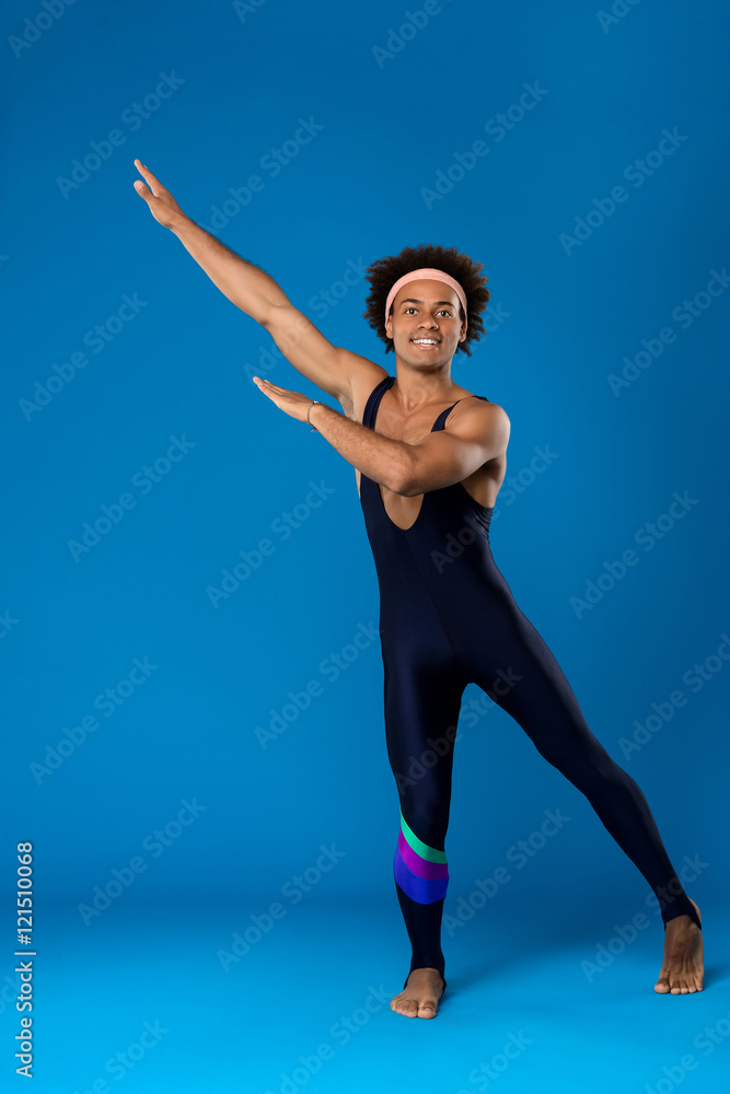 Obraz premium Sportive african man warming up, training over blue background.