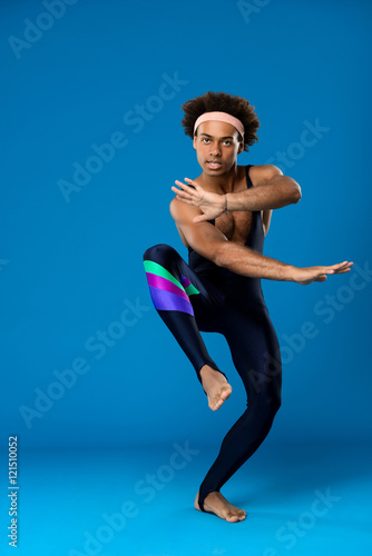 Fototapeta Naklejka Na Ścianę i Meble -  Sportive african man training, fooling over blue background.