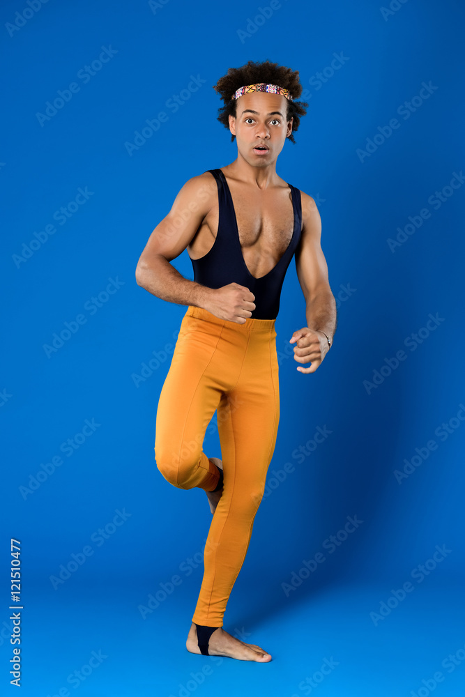 Sportive african man training martial poses over blue background.