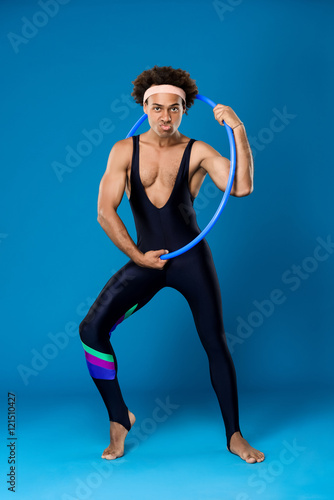 Sportive african man posing with hoop over blue background.