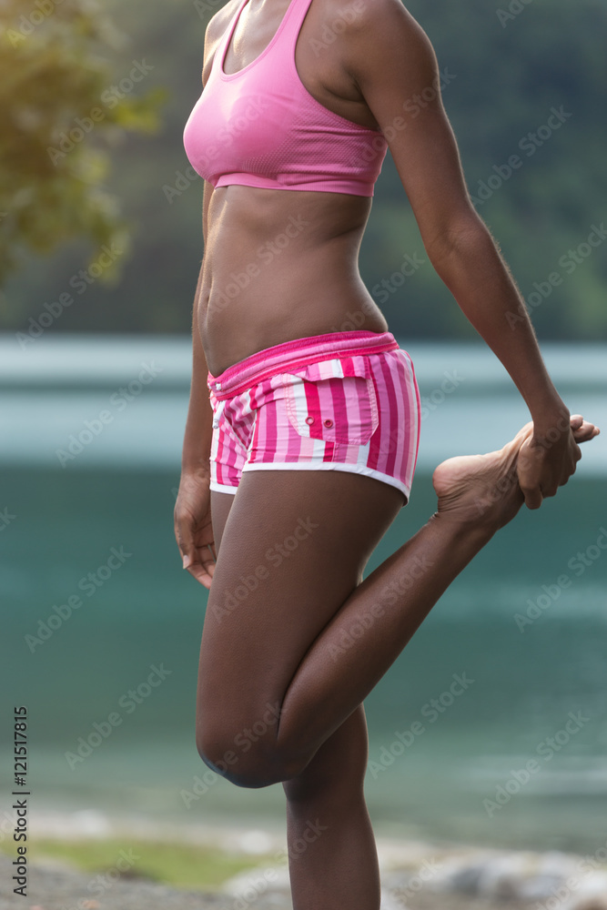 Young afro american woman in yoga pose on the beach