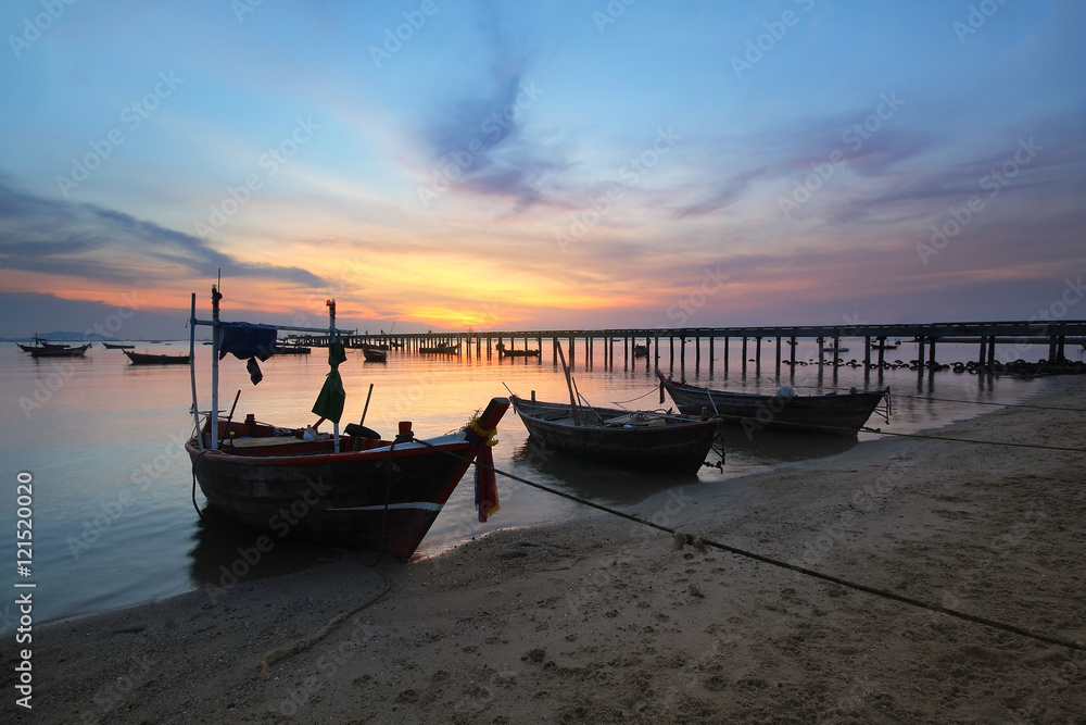 Small fishing boats moored beached on the beach during time the sunset and the beautiful natural of the colorful sky at Bang Phra beach , Chonburi province in Thailand