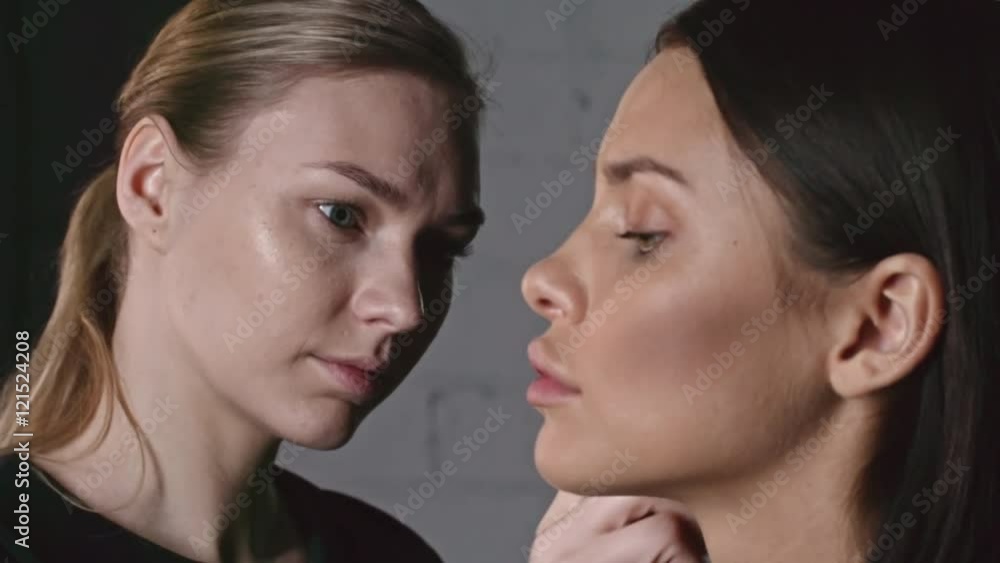 Studio shot of professional makeup artist working with brush to apply powder to face of attractive model Studio shot of professional makeup artist working with brush to apply powder to face of attractive model