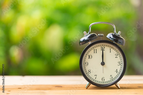clock on wood table in the green garden time at 12 o'clock