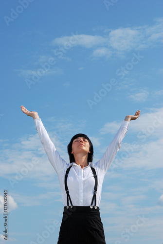 Woman standing on grass on background of blue sky © crewcut