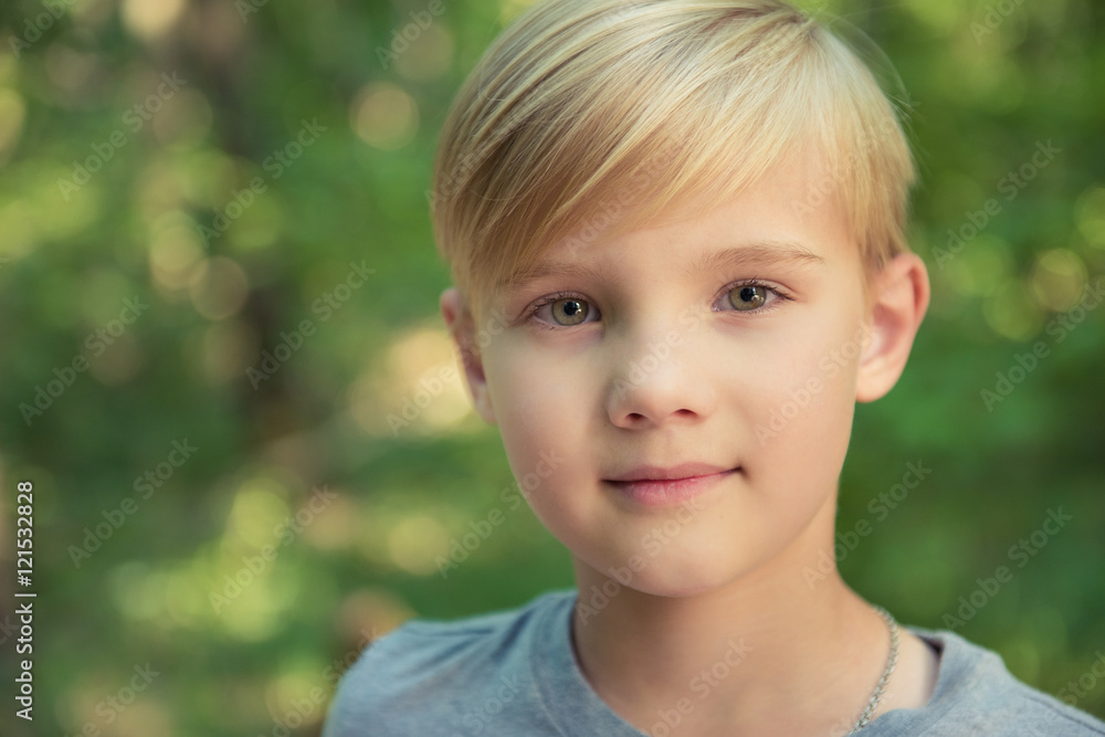 Portrait of a little boy with blonde straw hair in sunny summer day on green blurred background Portrait of a little boy with blonde straw hair in sunny summer day on green blurred background