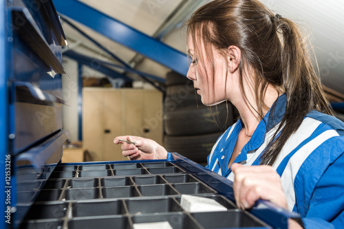 Female Mechanic Selecting Screw From Drawer At Garage