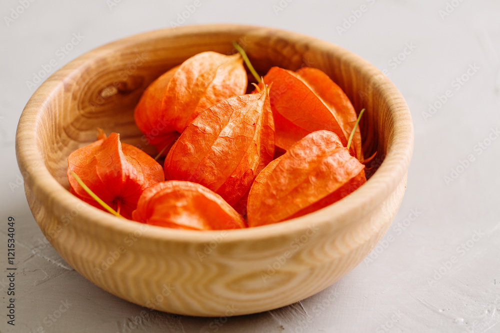 Red flowers physalis in wooden bowl