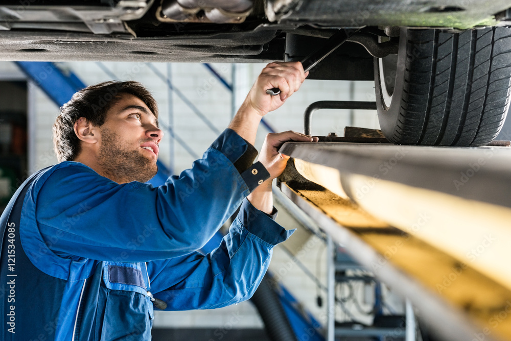 Mechanic Changing Tire From Suspended Car At Automobile Shop Mechanic Changing Tire From Suspended Car At Automobile Shop