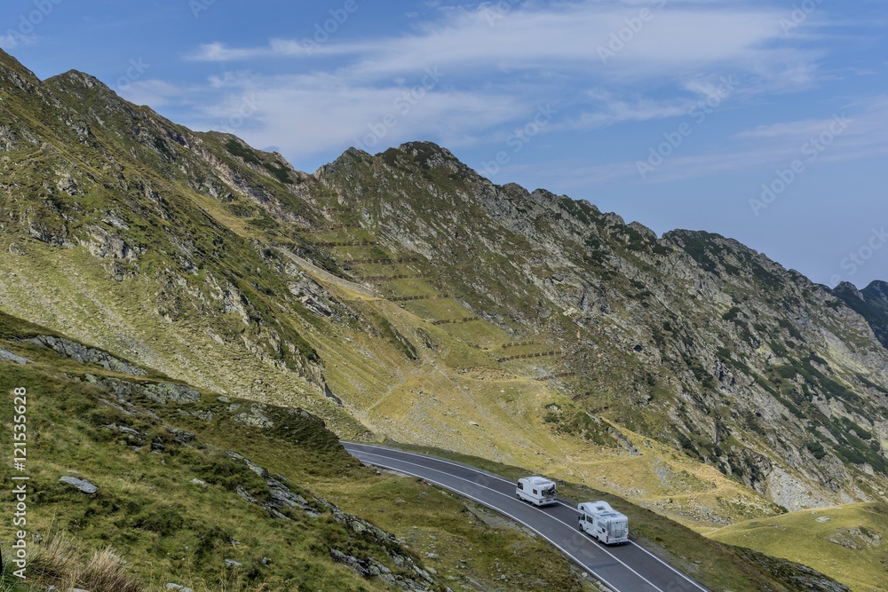 Mountain landscape with road and moving caravan travel trailers. Transfagarasan mountain road view.