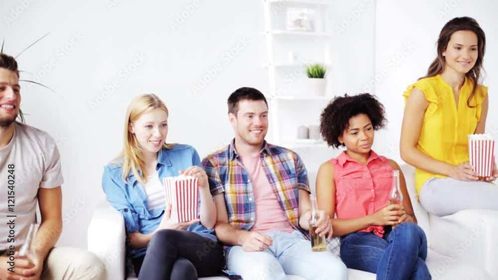 friends with popcorn and beer watching tv at home friends with popcorn and beer watching tv at home