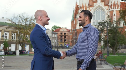 Two businessman are meeting and giving a handshake to each other. City background