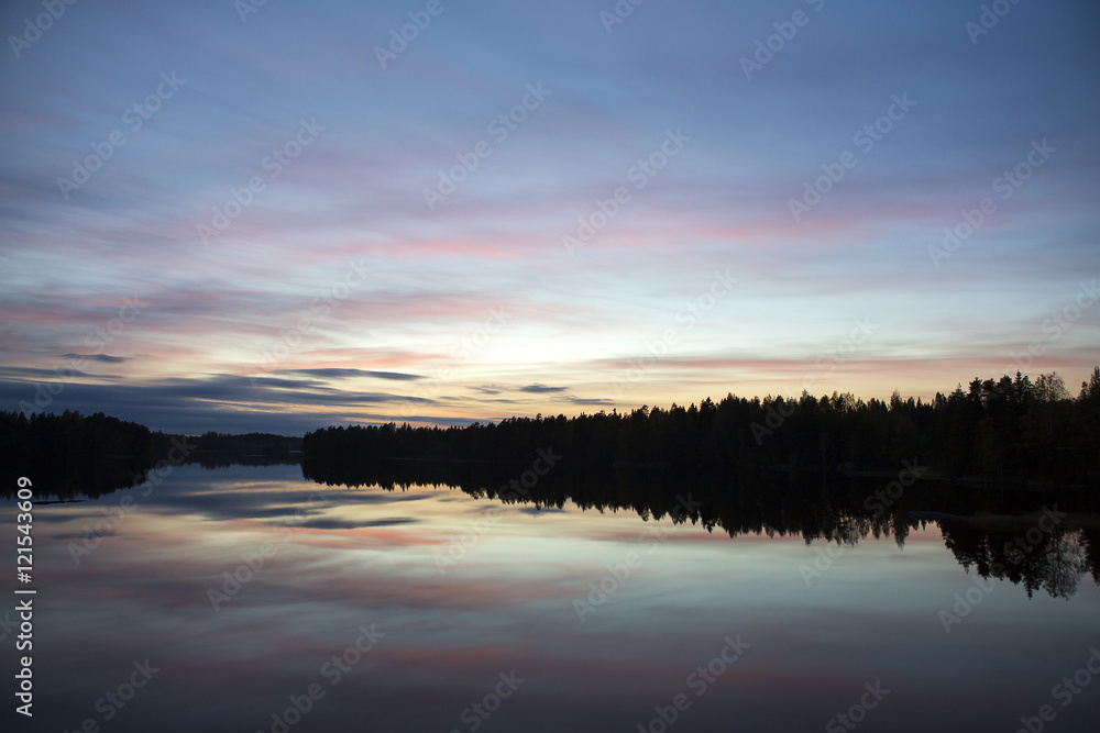 Obraz premium Calm evening at the lake. Some clouds are in the sky. Colorful sky. Silhouette forest.