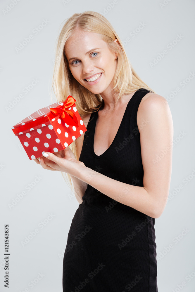 Smiling young woman in black dress holding gift box Smiling young woman in black dress holding gift box