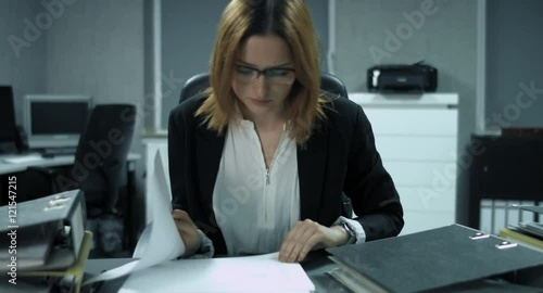 4K: Eine junge Büroangestellte überarbeitet Dokumente um sie abzuheften. Die Hitze lässt ihre Konzentration schwinden.