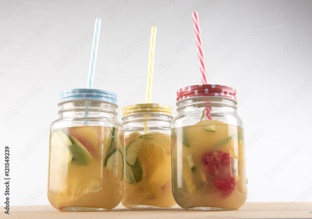 Three glass jars with colourful straws filled with fruit juice and pieces of cut up fruit. Taken on a white background. Three glass jars with colourful straws filled with fruit juice and pieces of cut up fruit. Taken on a white background.