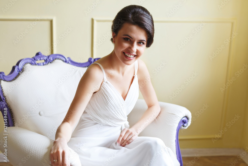 Smiling woman in white dress sitting on armchair Smiling woman in white dress sitting on armchair
