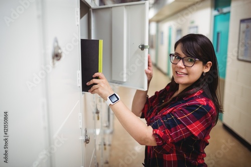 Female student keeping her book in the locker