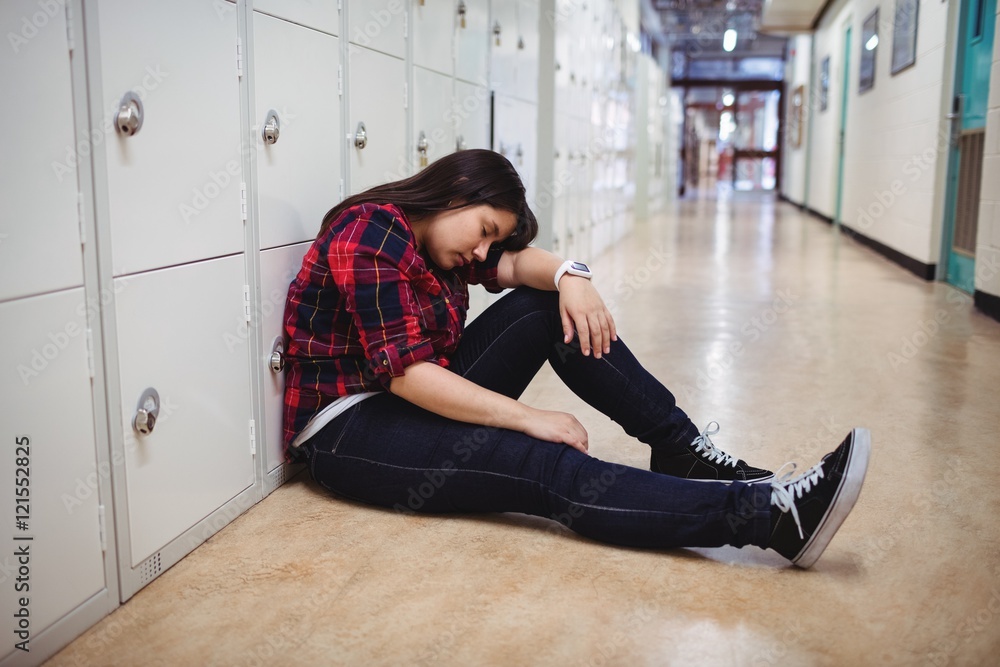 Depressed female student sitting in locker room Depressed female student sitting in locker room