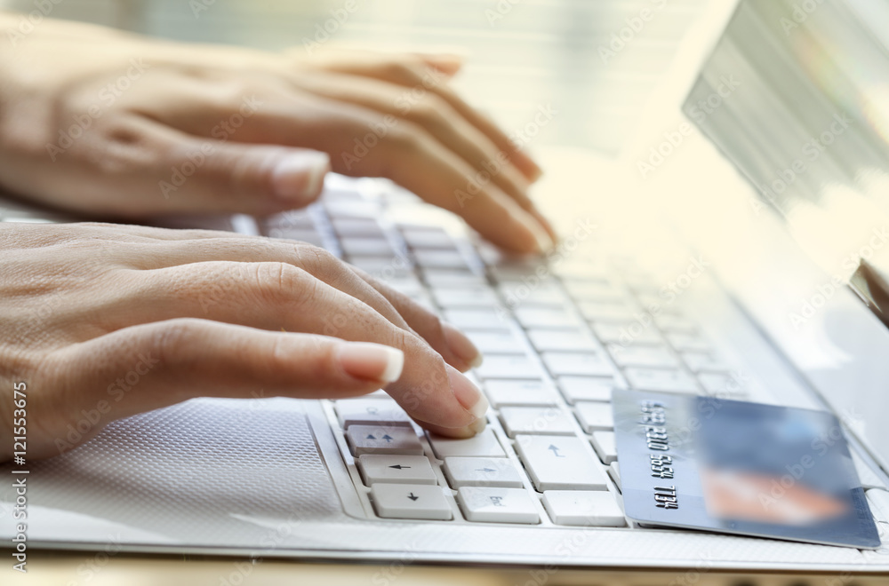 Hands holding credit card and using laptop Hands holding credit card and using laptop