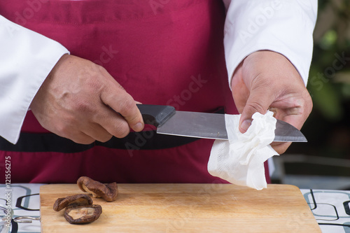 Chef hand cleaning knife before cooking