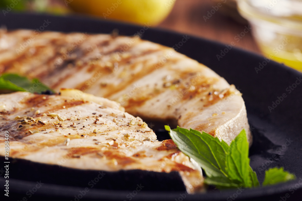 grilled swordfish slices in a cast iron pan on a wooden table