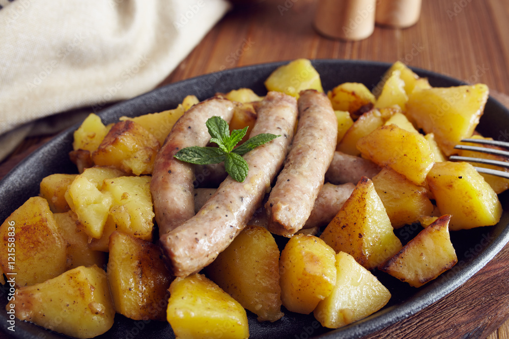 roasted sausages and potatoes on a wooden table roasted sausages and potatoes on a wooden table