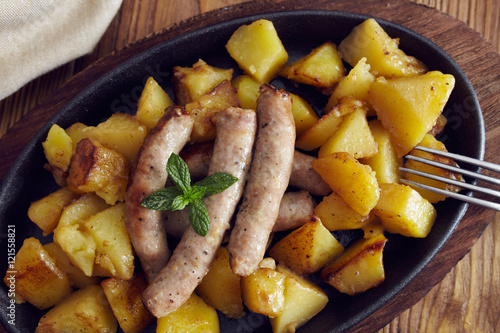 roasted sausages and potatoes on a wooden table