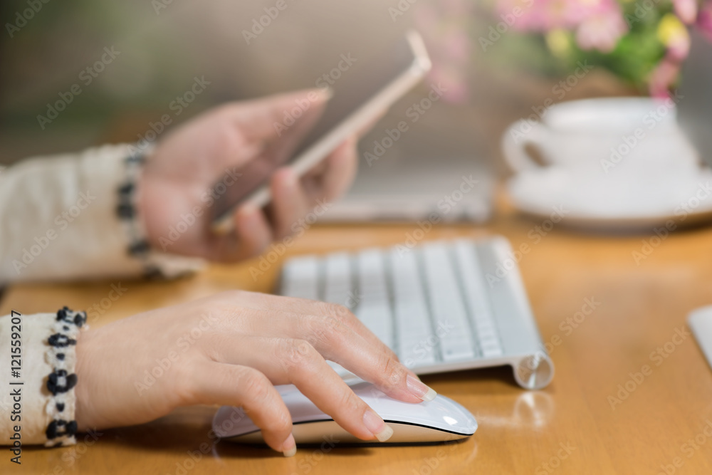 Close-up of woman hands click mouse and  smart phone   