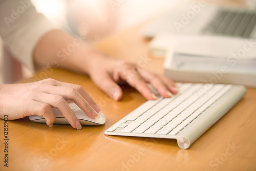 Close up of woman hands using mouse and keyboard.