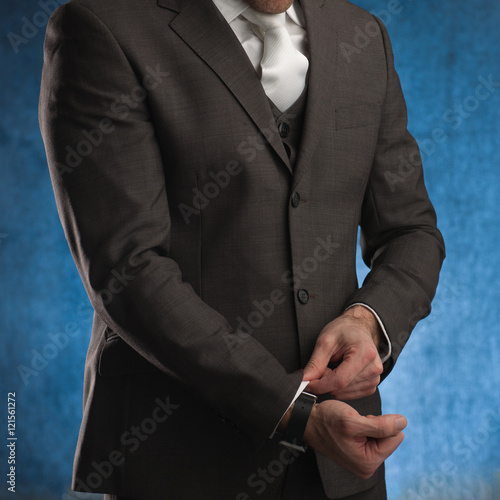Foto Business man adjusting his sleeve, on a blue background, stock picture