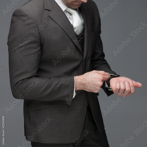 Quadro em tela Business man adjusting his sleeve, on a grey background, stock picture