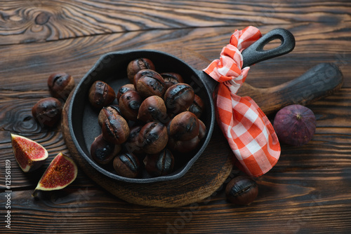 Frying pan with roasted chestnuts in a rustic wooden setting
