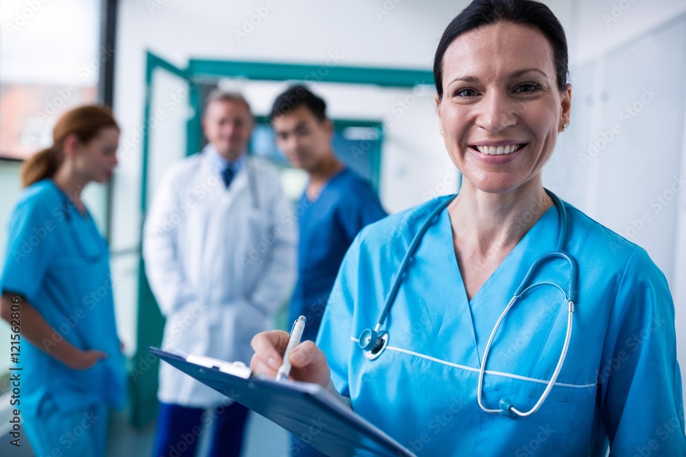 Portrait of smiling surgeon writing on clipboard Portrait of smiling surgeon writing on clipboard