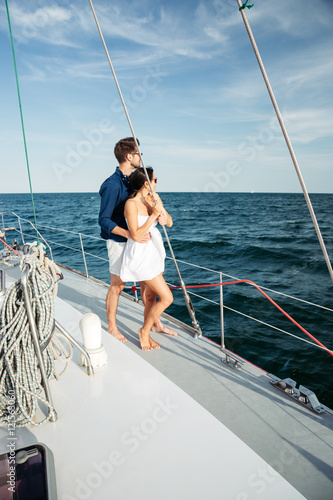 Beautiful happy couple standing on a yacht © Drobot Dean