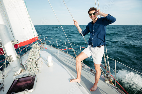 Man looking forward and smiling while standing on the yacht © Drobot Dean