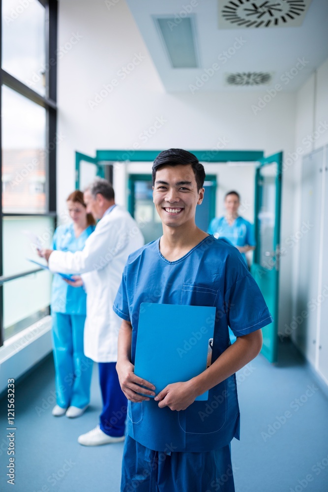 Smiling male surgeon holding a clipboard in corridor Smiling male surgeon holding a clipboard in corridor