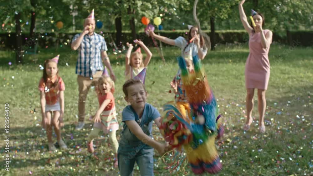 Little boy striking pinata with wooden bat while playing at birthday ...