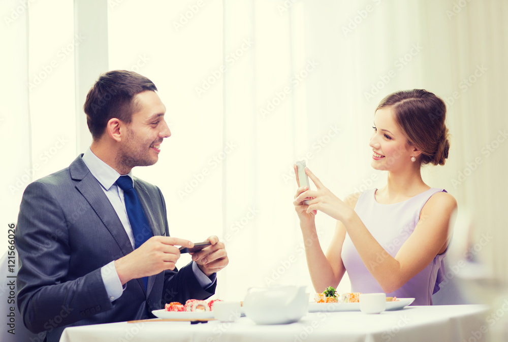 smiling couple with sushi and smartphones