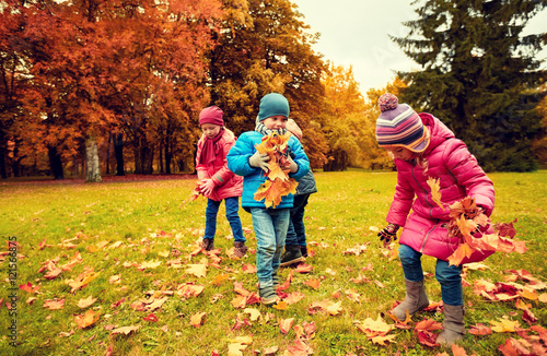group of children collecting leaves in autumn park