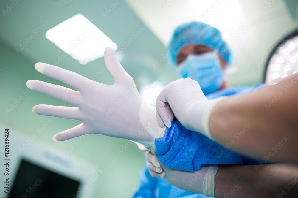 Nurse helping a surgeon in wearing surgical gloves Nurse helping a surgeon in wearing surgical gloves