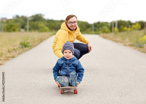 happy father and little son riding on skateboard