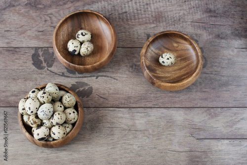 Three wooden bowls with quail eggs. Rustic wood background, diffused natural light. A different type of concept image for Easter. Copy space.