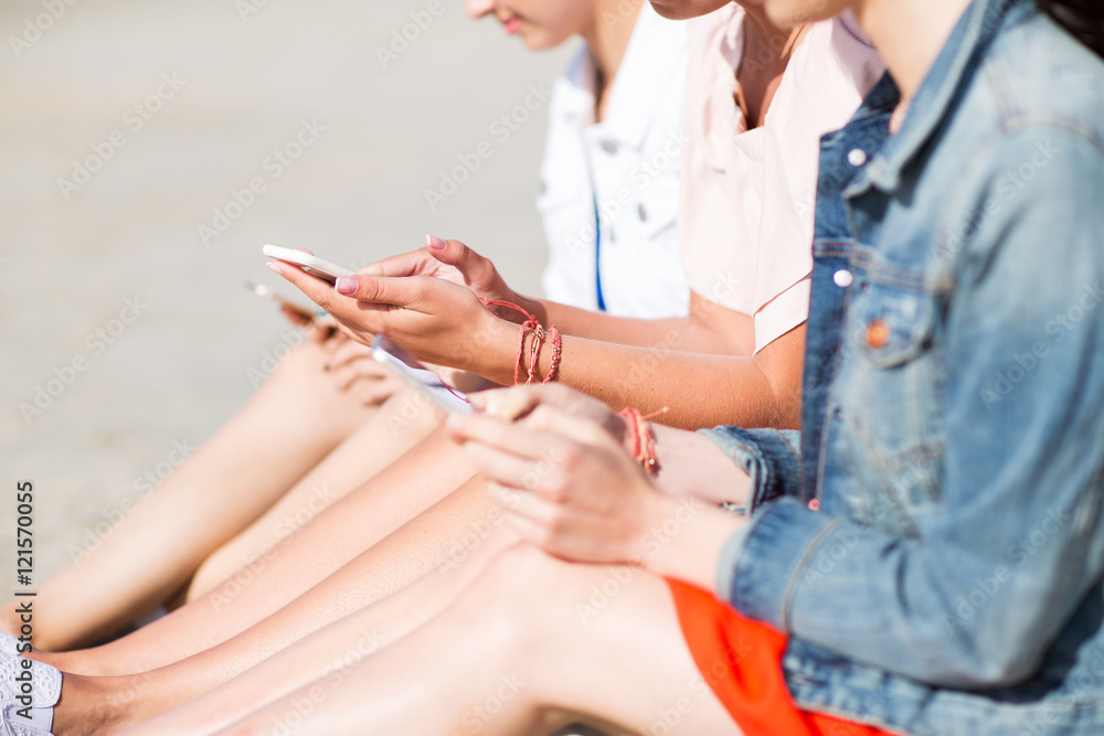Fototapeta premium close up of young women with smartphones on beach